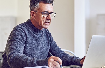 Image of man taking notes from his computer