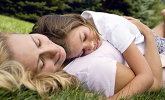 mom and daughter rest in the grass