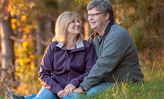 middle-aged couple sits on the bank of the river during fall