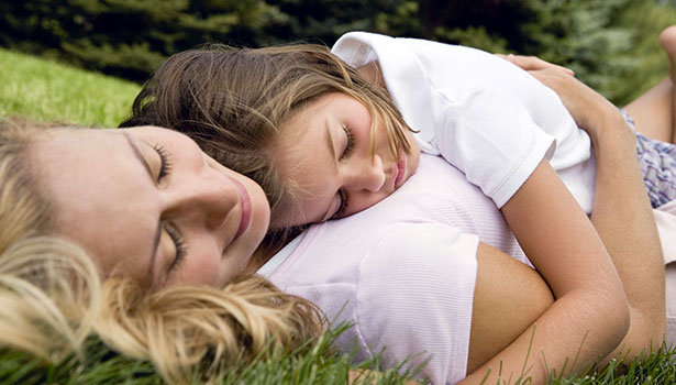 mom and daughter sleep in the grass